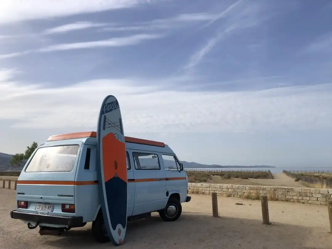 Combi Volkswagen vintage avec planche de surf sur une plage en Corse