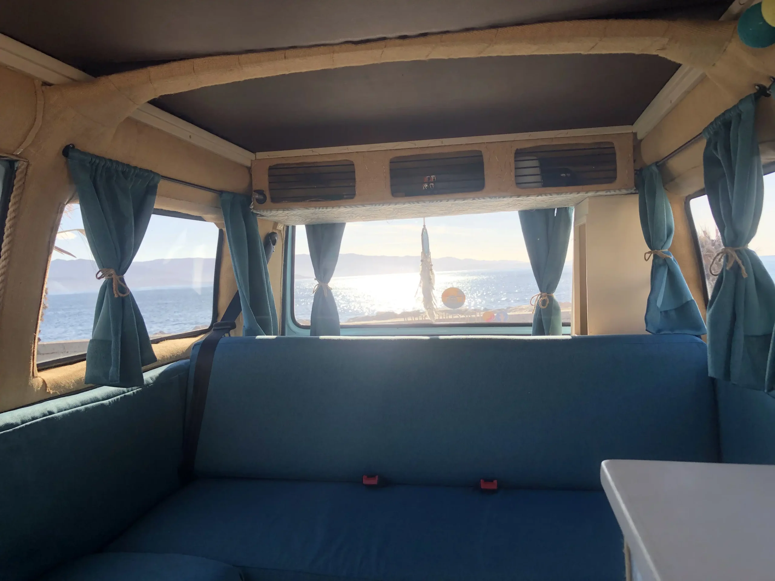 Intérieur d’un combi Volkswagen aménagé avec vue sur la mer en Corse