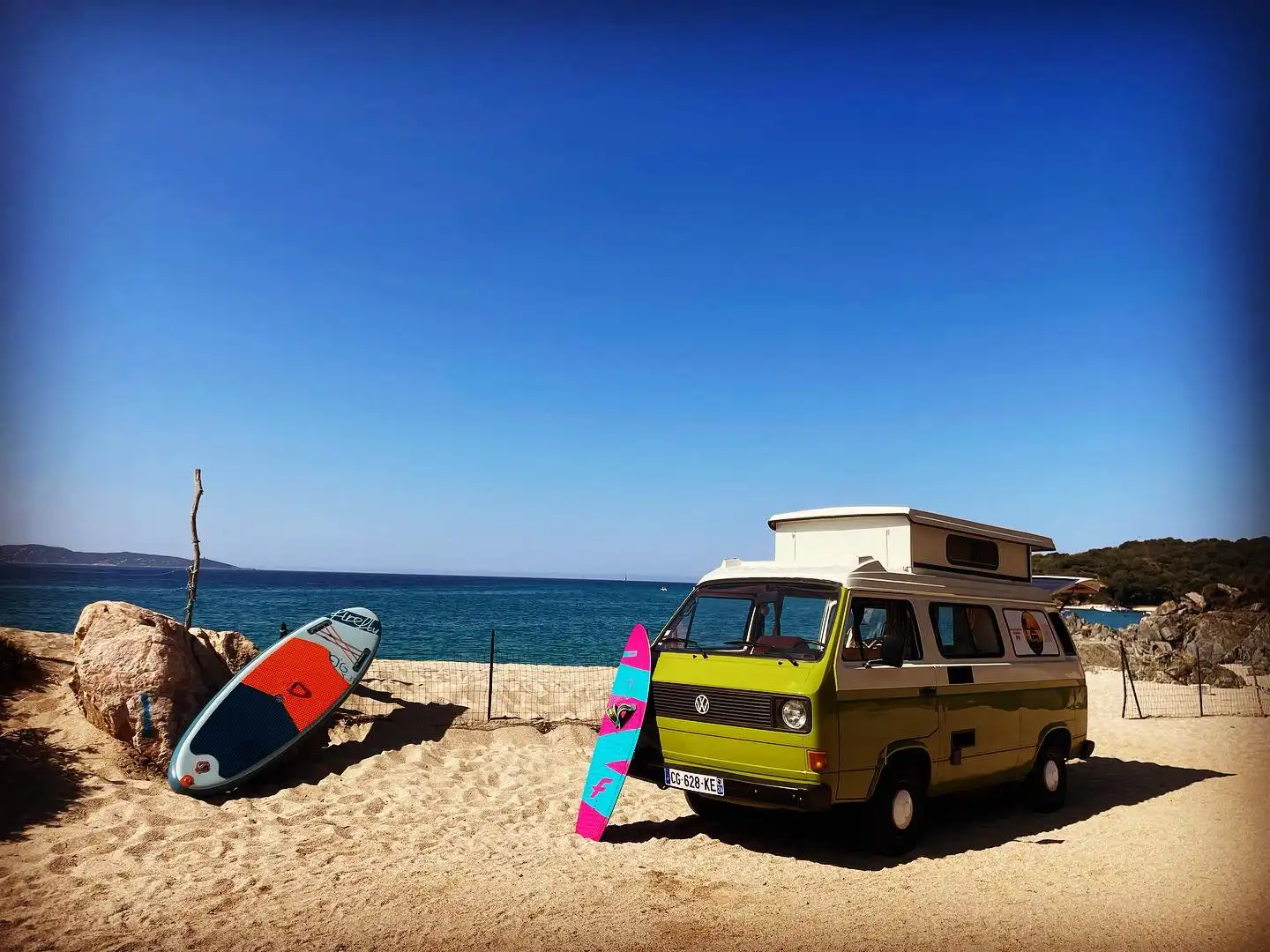 Van vintage sur une plage en Corse avec une planche de surf